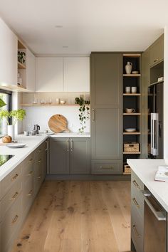 a large kitchen with wooden floors and gray cabinetry, white counter tops and wood flooring