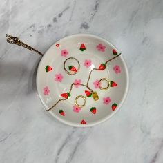 a white plate with pink flowers and gold rings on it, next to a spoon