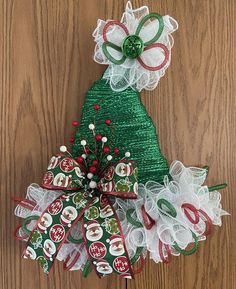 a green christmas tree with white and red bows on it's head, sitting on a wooden surface