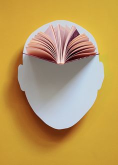 an open book sitting on top of a white plate next to a yellow tablecloth