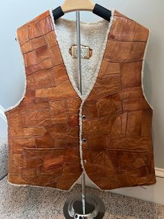 A rare GEM! Vintage 1970s patchwork leather vest with shearling lining. Made in Mexico, size 46. Has side pockets.  MEASUREMENTS (garment measured flat): Shoulder to shoulder: 16" Shoulder to bottom (front): 25" Back (neck to bottom of vest): 33" Arm Hole: 11" Please read description carefully and view all photos. I describe and photograph all condition issues that I am aware of. I do my best to research and give the most accurate information regarding the item, but no one is perfect! Please do your own research if you are unsure about the item(s). Additional photographs are available upon request. If you have questions about any item, please contact me before purchasing. Unless stated otherwise, all vintage clothing items are pre-owned, one in stock, and are sold as-is with no warranty. I Rugged Leather Vest Outerwear, Brown Patchwork Vest For Fall, Brown Rugged Vest For Winter, Brown Rugged Winter Vest, Rugged Brown Winter Vest, Vintage Leather Vest Outerwear, Leather Winter Vest With Pockets, Brown Sleeveless Vest With Faux Fur Lining, Leather Gilet