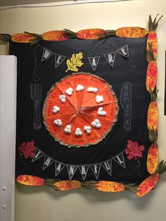 an orange and black paper plate with white cotton balls on it is hanging from the wall