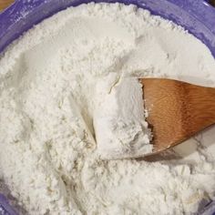 a wooden spoon in a blue bowl filled with flour