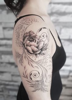 a woman's arm with a flower and swirls tattoo on her left shoulder