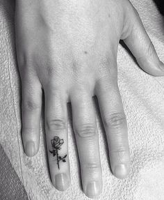 a person's hand with a small tattoo on the middle finger and a cross in the middle