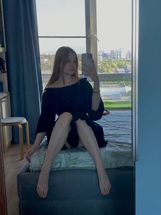 a woman sitting on top of a bed taking a selfie