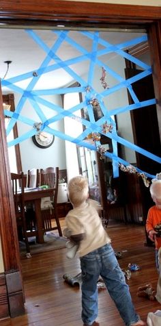 two young boys standing in front of a mirror with blue streamers hanging from the ceiling