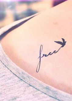 a small tattoo on the back of a woman's shoulder that reads free with a bird flying above it