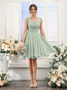 a woman standing in front of flowers wearing a green bridesmaid dress and heels