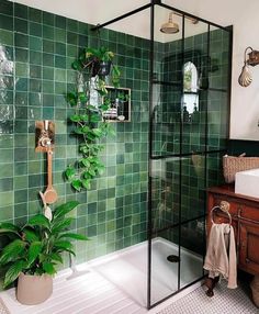 a bathroom with green tiles and plants on the wall