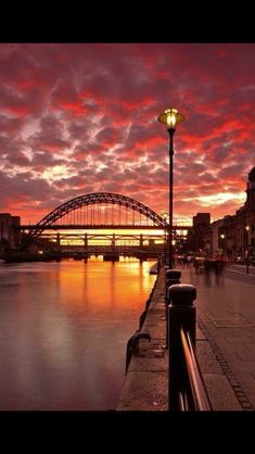 the sun sets over a bridge and river