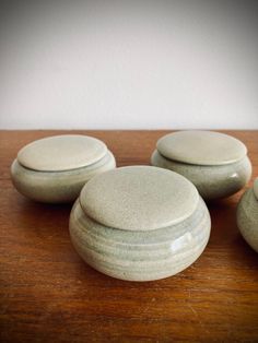 four white ceramic containers sitting on top of a wooden table