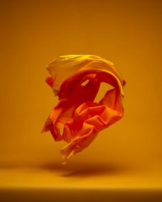 a yellow and orange flower is in the middle of a brown background with light coming through it