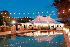 a tent with lights hanging over it next to a pool