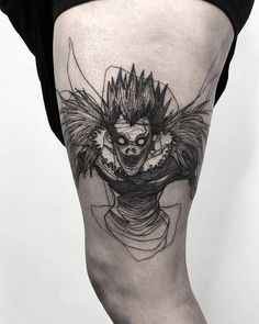 a woman's leg with a tattoo design on the thigh and an image of a demon