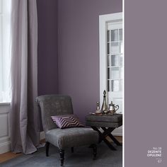 a living room with purple walls and a gray chair in front of the window,