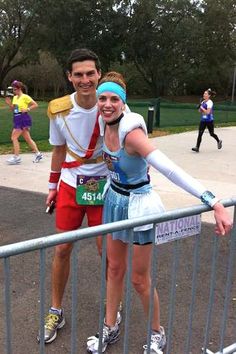 a man and woman standing next to each other near a metal fence at a marathon