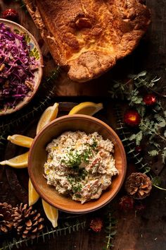 a wooden bowl filled with coleslaw next to two slices of bread and lemon wedges