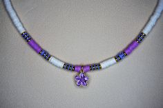 A trendy surfer necklace, which is similar in fashion to those worn by Kiara on Outer Banks; interpreted with purple, powder blue and white Heishi beads (polymer clay beads) and bright, shiny gold (metallic) Heishi beads. The necklace measures approximately 16 inches and will lie at the collar bone, on most people. It is finished with a gold plated magnetic clasp, and other gold plated findings, and features a lovely, purple enamel flower charm (measuring 13mm x 13mm). This necklace drapes well Beach Jewelry With Colorful Purple Beads, Purple Jewelry With Colorful Beads For Beach, Handmade Purple Beaded Necklaces For Beach, Handmade Purple Beach Jewelry, Purple Tiny Beads Necklace For The Beach, Purple Tiny Beads Necklace For Beach, Handmade Purple Beach Necklaces, Purple Necklaces With Tiny Beads For The Beach, Handmade Purple Necklaces For Beach