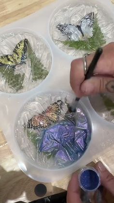 the person is painting butterflies on plastic plates