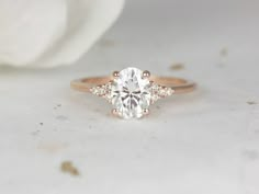 a close up view of a diamond ring on a white surface with a flower in the background