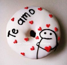 a white donut decorated with red hearts and the words te amo on it