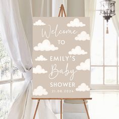 a welcome sign sitting on top of a easel in front of a white curtain