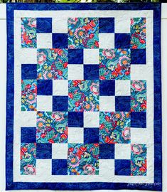 a blue and white quilt hanging on the side of a wall