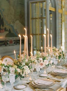 a long table is set with white and gold plates, silverware, and floral centerpieces