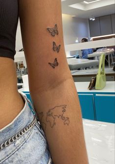 a woman's arm with butterflies and a world map tattoo on the left side