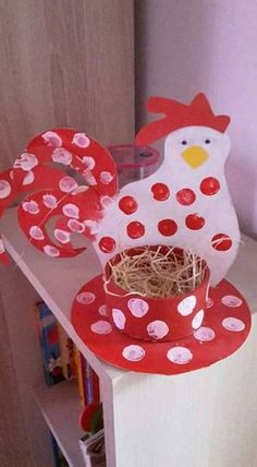 a paper mache chicken sitting on top of a shelf next to a bird's nest