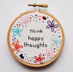 a cross stitch hoop with the words think happy thoughts