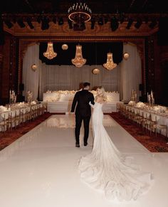 a bride and groom standing in front of a banquet table with chandelier hanging from the ceiling