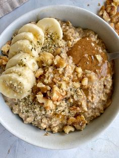 a bowl of oatmeal with bananas and nuts on the side next to a spoon