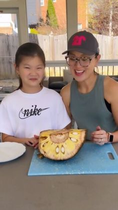 two people sitting at a table with a large piece of fruit