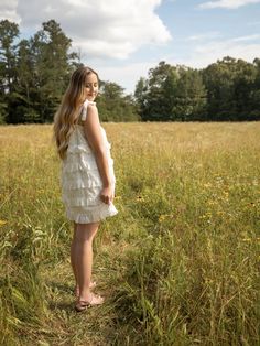 This eyelet ruffled mini dress displays an upper chest drawstring, bow detail, self-tie ribbon straps, and ruffled edge layers. The model is wearing a size small Ruffled Tie Straps Mini Dress For Garden Party, Garden Party Mini Dress With Ruffled Tie Straps, Spring Mini Dress With Lace Trim And Tiered Skirt, Casual Ruffled Mini Dress With Straps, Tiered Lace Trim Mini Dress For Garden Party, Casual Mini Dress With Ruffled Straps, Sundress Style Tiered Dress With Ruffles For Daywear, Ruffled Mini Dress, Dress Display