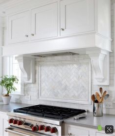 a stove top oven sitting inside of a kitchen next to white cabinets and counter tops