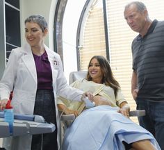 three people standing around a woman in a hospital bed