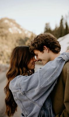 a man and woman standing next to each other with their arms around each other while looking at each other