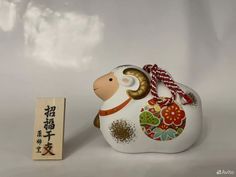 a small white ceramic animal next to a wooden block with chinese writing on the side