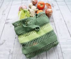 a green crocheted bag sitting on top of a wooden table next to vegetables