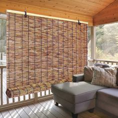 a couch sitting on top of a wooden floor next to a window covered in bamboo blinds