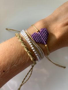 a woman's arm with three bracelets and a purple heart on the wrist