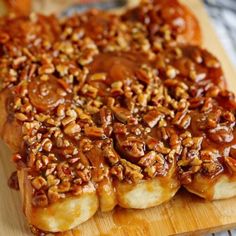 a wooden cutting board topped with sliced bananas covered in caramel and pecan flakes