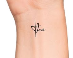 a small cross tattoo on the wrist that says,'love'in cursive font