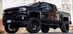 a black truck parked in front of a brick wall