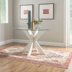 a glass table with two vases sitting on top of it next to a rug