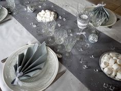 the table is set with silver and white plates, napkins, and candlesticks