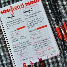 a notebook with some writing on it next to markers and pens in front of a checkered table cloth