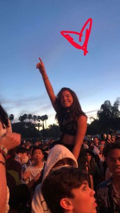 a girl is flying a kite in the air at an outdoor concert with other people